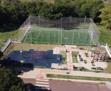 Meu Campinho em Maringa. O espaço tem um campo de futebol de grama sintética, playground com piso emborrachado e com iluminação, bicicletários, bebedouro, mesas de jogos, floreiras e lixeiras -  