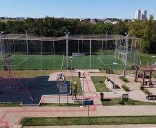 Meu Campinho em Maringa. O espaço tem um campo de futebol de grama sintética, playground com piso emborrachado e com iluminação, bicicletários, bebedouro, mesas de jogos, floreiras e lixeiras -  