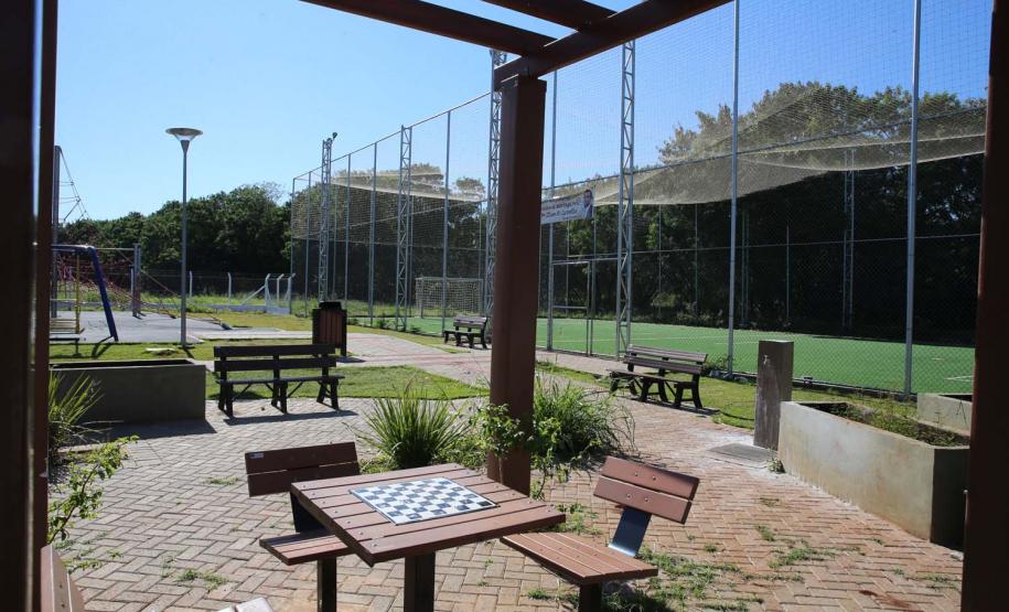 Meu Campinho em Maringa. O espaço tem um campo de futebol de grama sintética, playground com piso emborrachado e com iluminação, bicicletários, bebedouro, mesas de jogos, floreiras e lixeiras -
