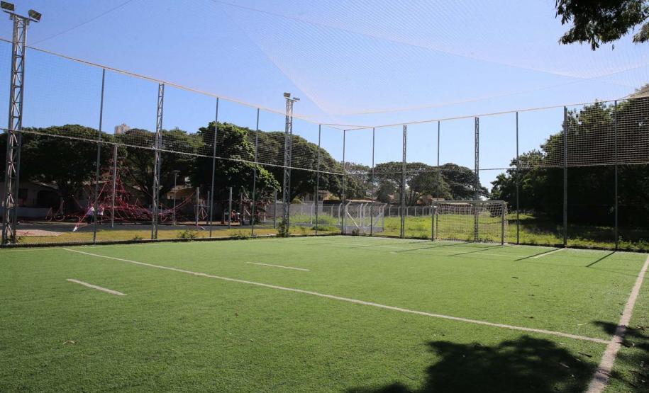 Meu Campinho em Maringa. O espaço tem um campo de futebol de grama sintética, playground com piso emborrachado e com iluminação, bicicletários, bebedouro, mesas de jogos, floreiras e lixeiras -