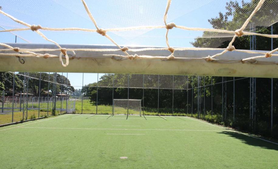 Meu Campinho em Maringa. O espaço tem um campo de futebol de grama sintética, playground com piso emborrachado e com iluminação, bicicletários, bebedouro, mesas de jogos, floreiras e lixeiras -